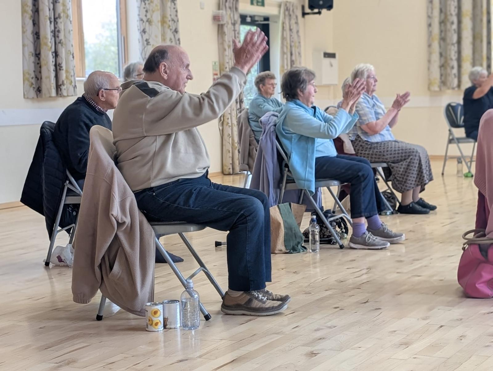 people doing seated exercise in a hall