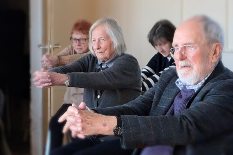 Seniors doing cool down exercises during a MOVEability seated chair exercise class